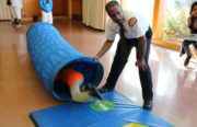 Assistant Fire Marshal Enrique Orduña watches and holds the nylon tubes as children crawl through after performing the stop, drop, and roll technique.
