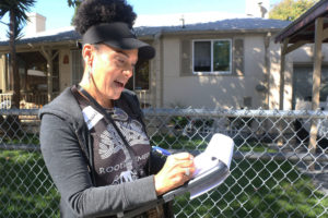 Donna Anderson marks on a map the house number she just visited in Sobrante Park as she makes her way through the neighborhood Saturday morning.