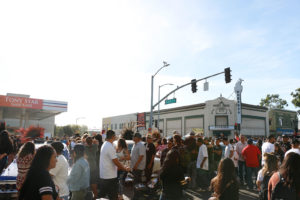 Families make their way past Tony Star Gasoline on 36th Avenue and International Boulevard, perusing classic cars with altars assembled on their hoods and in open trunks, as the festival nears its final hours.