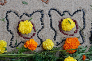 Just inside the outlines of Hidalgo’s altar, or ofrenda, lie black and red beans in the shape of butterflies. He says a few children helped him arrange the seeds, which symbolize a cycle, including death. He says things left on the altar are meant to entice ancestors to visit on the Day of the Dead.