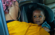 James Cox buckles in her daughter, Yemaya, as they head to Creative Explorers—a child care center that meets Cox's unique needs.