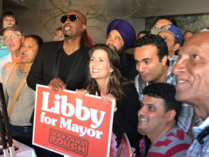 A group of “Libby for Oakland” volunteers yell “Libby!” as a campaign staffer takes a picture of the group, with Schaaf supporter and recording artist MC Hammer (left) and Schaaf (right).