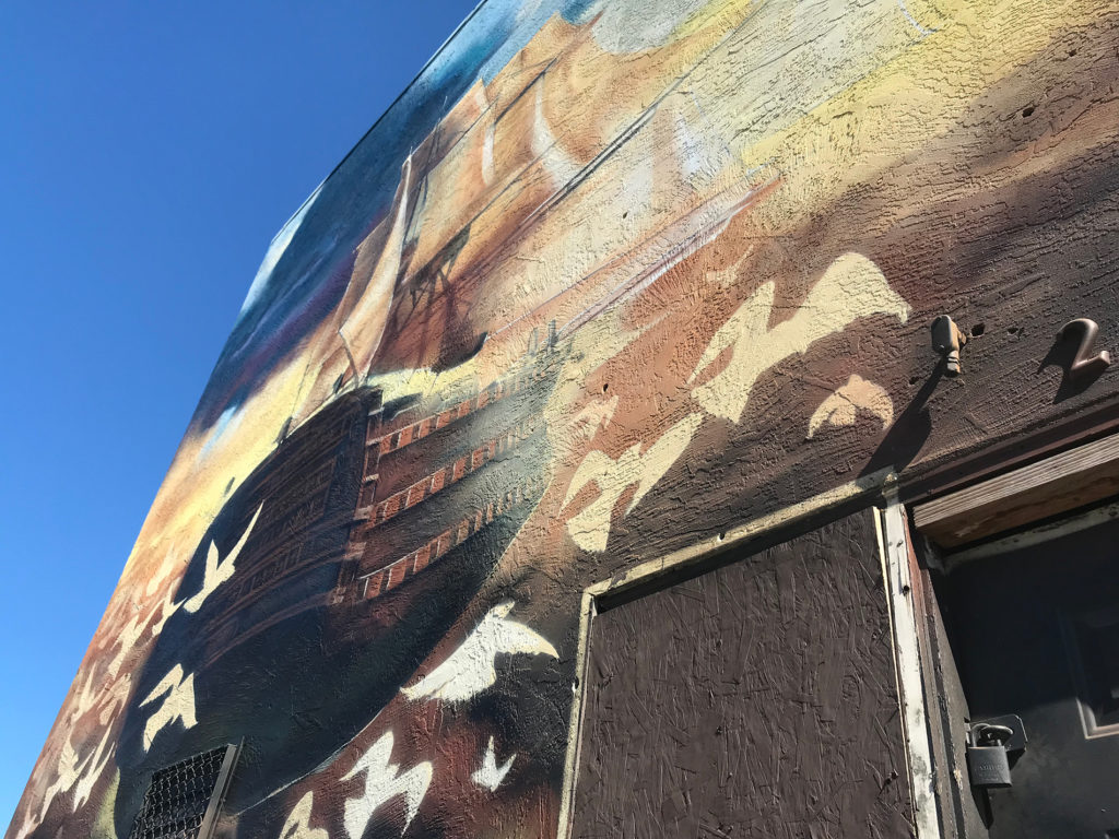 A mural honoring the victims of the Ghost Ship fire glows in the late morning sun.