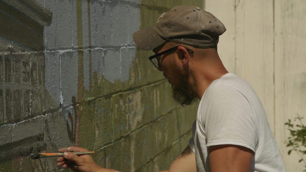 Dave Young Kim painting a mural in Oakland. Photo by Julie Chang.
