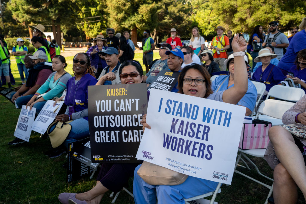 Kaiser Permanente workers with pro-union signs rally at Mosswood Park on Labor Day.