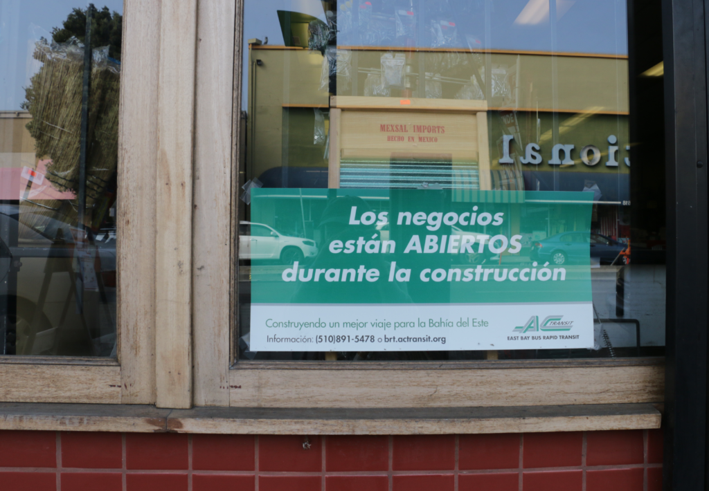 A sign in a window that reads "Los negocios están ABIERTOS durante la construcción"