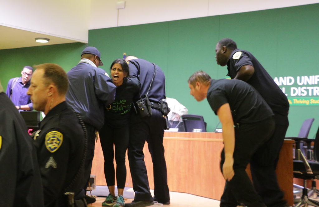 A protester demonstrating against school closures is taken into custody by Oakland School Police. Photo by Michelle Pitcher.