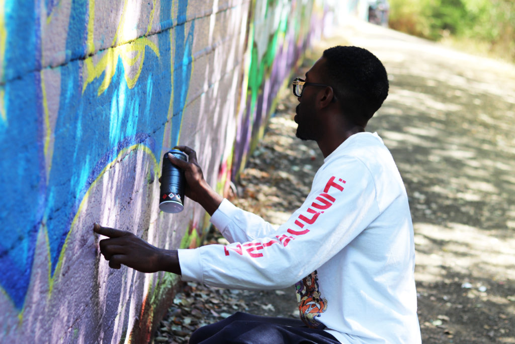 Maliwop steadies himself with one finger as he fills in his outline.