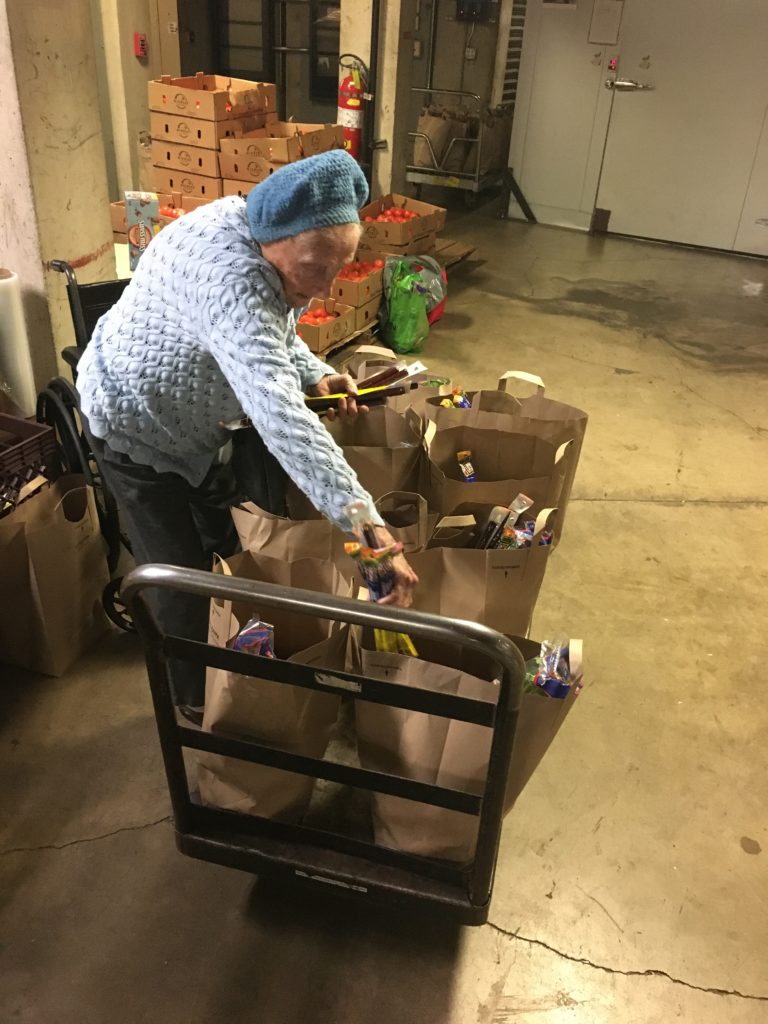 Rose packs a Slim Jim into brown bags in the basement of the Mercy Retirement and Care Center.