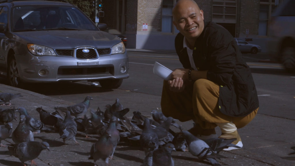 Nan Guang, a monk at the Pu Gaung Temple in Oakland, feeds dozens of pigeons on Harrison Street. Photo by Jocelyn Tabancay