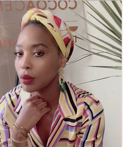 This is a picture of Latoya McInnis. She is wearing a striped shirt and she has head wrap on her head. She has earrings that are ivory and green.
