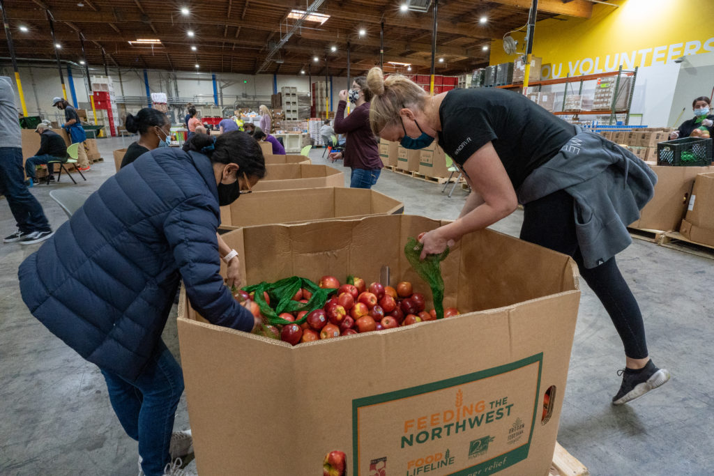 Christy Valencia (left) and Jill Elliott bag apples for the Alameda County Community Food Bank. (Michael Slaten/Oakland North)