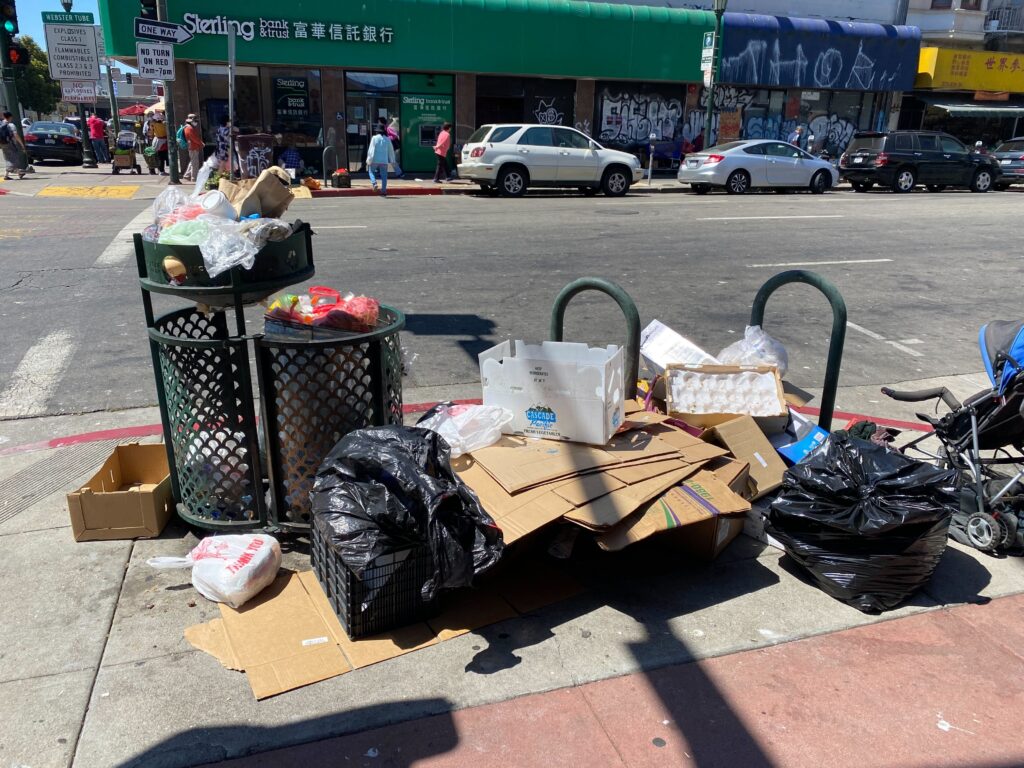 Piles of trash sit on a sidewalk in Oakland Chinatown