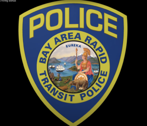 A closeup of the BART police logo which shows a roman warrior with a spear by a golden bear in front of a bay filled with Middle Ages sailing vessels.