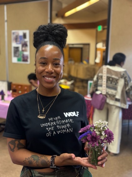 A young woman in a office holding a small small bouquet.