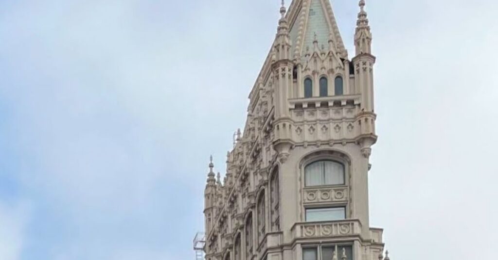 Just the top of the Gothic-designed stone Cathedral building with spires on a narrow design, against a blue sky.