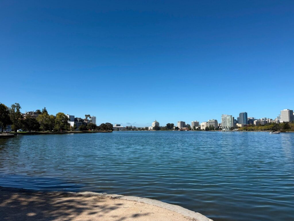 A blue lake takes up most of the picture, with a few tall buildings on the bank at the far end, under a very blue sky.